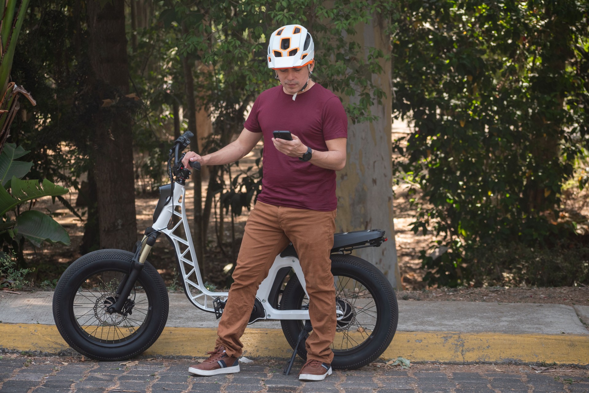 Latin man riding his electric bicycle and looking at his phone